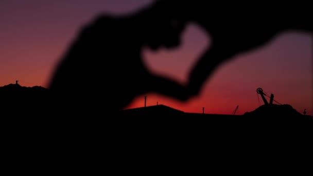美しい夕日の背景に手で作られた心 — ストック動画