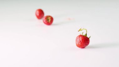 Çilek güzel bir şekilde beyaz bir zemine düşüyor, yakın plan. Beyaz arka plan..