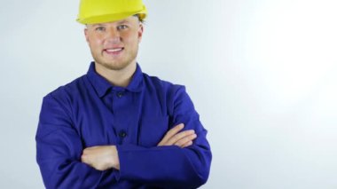 Bir müteahhit portresi, bir adam gülümsüyor, üniformalı genç ve yakışıklı bir işçi ve bir miğfer, beyaz arka planda, yakın plan,.