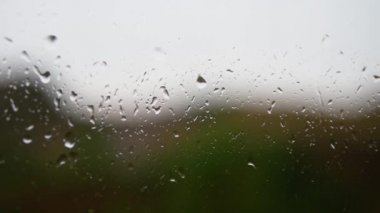 Pencereden aşağı akan yağmur damlaları, yakın çekim, makro, pencereyi yıkayan yağmur. Yağmurlu duvar kağıdı..