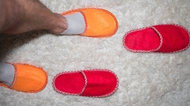 Erkek bacakları, renkli terlikler içinde ayaklar, üst manzara, yerde terlikler..