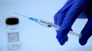 Bir doktor koronavirüs enfeksiyonuna karşı aşı yapar. Bir tıp çalışanının elinde virüs için bir şırınga vardır.