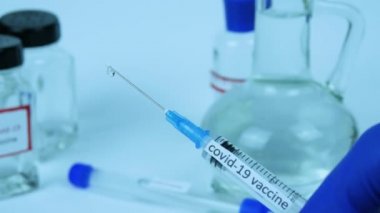 Coronavirüs aşısı olan bir doktorun elindeki şırınga, salgın için tedavi, yakın çekim.