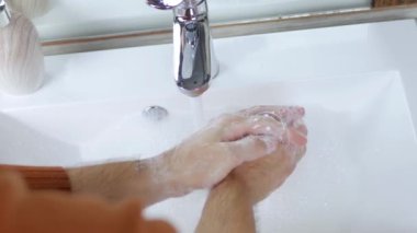 Musluğun altında su ile ellerini yıkamak, vücudun temizliğini sağlamak, kendini Covid-19 hastalığından korumak, yakın çekim.