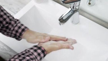 Yıkanan ellerin en üst görüntüsü, adamım, genç adam kirli mikropları ve bakterileri ellerinden temizler, ellerini sabunla yıkar, yakın plan