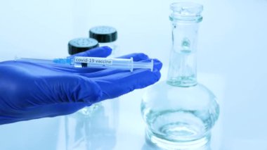Coronavirus enfeksiyonuna karşı bir aşı, bir doktorun elinde, ilaç gösterimi, yakın plan, aşı geliştirme laboratuarı