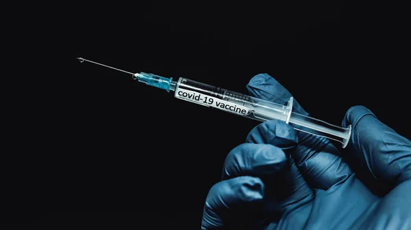 ワクチン注射器 薬の滴が針を流れ 医療用手袋の手は Covid クローズアップに対するワクチン注射器を保持しています — ストック写真