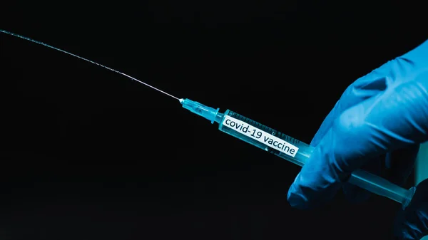 注射器から注射器のジェットは 医療専門家は 黒の背景に Covid 注射器のテキストコロナウイルス クローズアップのための薬を示しています — ストック写真