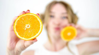 Beyaz arka planda, bir kızın ellerinde bir portakalın yakın plan fotoğrafı.