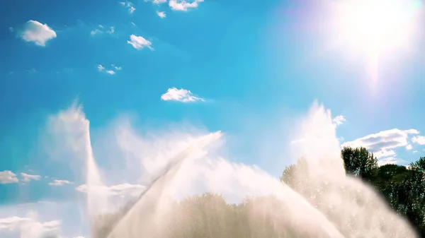 美しい空と太陽を背景にした噴水 高さのある水の流れ 風に揺れる — ストック写真