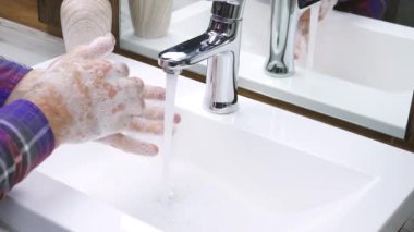 Ellerini musluğun altında suyla yıkamak, yakından. Bir adam ellerindeki kiri temizler, vücudunu dezenfekte eder.