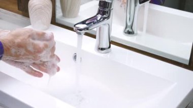 Bir adam ellerini sabunla yıkıyor, ellerindeki kiri iyice temizliyor, vücudunun temizliğiyle ilgileniyor, el hijyeni, yakın çekim.