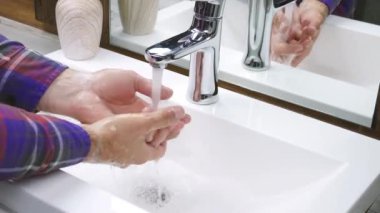 Elle yıkama yapan kişi lavaboda akan suyla sabun yıkıyor, ellerindeki kiri temizliyor, Coronavirüs 'ü önlemek için el hijyenini yıkıyor.