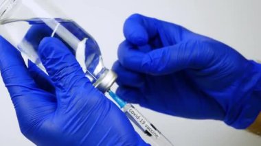 Bir doktor şırıngayı koronavirüs enfeksiyonu için aşıyla dolduruyor, yakın çekim. Bir pandemiği tedavi ve önleme aracı. Şırıngada aşı.