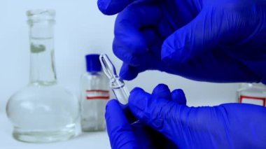  Doktor parmaklarıyla tıbbi ampulü vuruyor. Enjeksiyon için ilacı kamçılıyor, yakın plan. Bir tıp çalışanı elinde aşı tutuyor.
