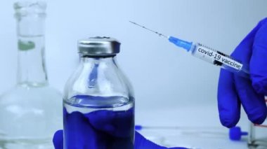 Koronavirüs enfeksiyonuna karşı bir test aşısı göstergesi. Bir doktor elinde virüsün ilacı olan bir şırınga tutuyor..