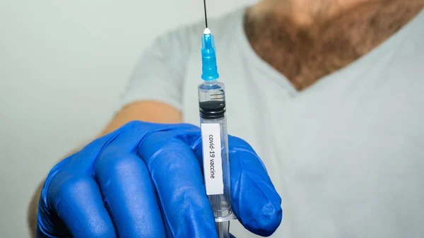 男性は手に注射器を持っています碑文のコロナウイルスワクチン クローズアップ — ストック写真