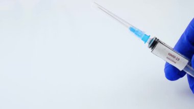 Coronavirus aşısı olan bir şırınga, bir tıp çalışanı elinde Covid-19 aşısı olan bir başlık, viral enfeksiyon için bir tedavi, yakın çekim.