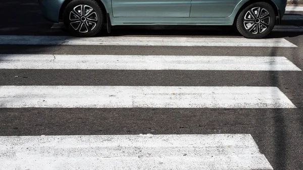 Zebra pedestrian marking with car,close-up, passing car on zebra crossing