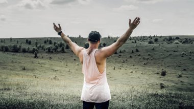 Doğada kollarını yana açmış bir adam, bir adam özgürlüğü gösterir, genç bir adam çayırdaki bir tarlada mutludur, yalnız bir adam uçuyormuş gibi görünür.