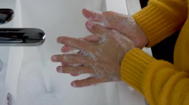 Musluğun altında ellerini sabun ve suyla yıkamak. Genç bir adam ellerindeki kirleri, vücut temizliğini ve sağlık hizmetlerini temizliyor.