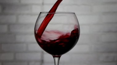 Bardağa şarap dök, bardağa kırmızı şarap dök beyaz tuğla duvara karşı, şarap yakın plan