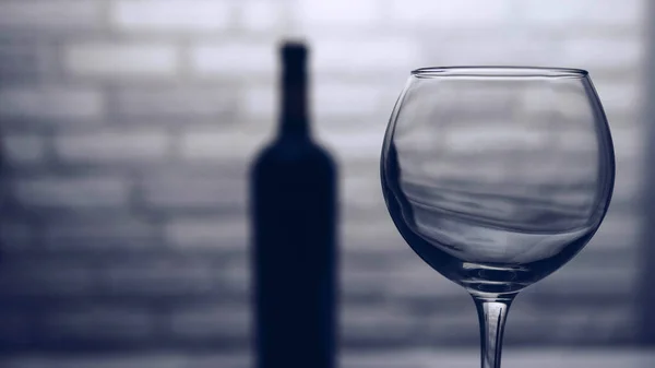Leeg Wijnglas Met Een Fles Wijn Een Bakstenen Muurachtergrond — Stockfoto