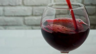 Tuğla duvarda kırmızı şarap bardağı, şaraplı bardağa yakın plan.