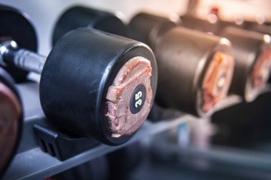 Kauçuk halterler spor salonunda duruyor, halterin kapağı yırtılmış ve hasar görmüş, spor aletleri tamir konsepti 