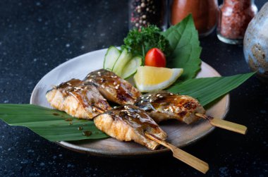 Teriyaki sosu kümesiyle ızgara saba balık şiş ve Japon tarzında hizmet vermektedir.