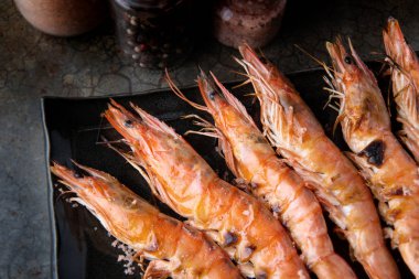 Izgara karides whith kömür karanlık gölge aydınlatma ile siyah tabak içinde yanan ateş hizmet.