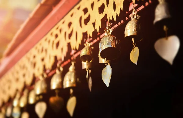 Little brass bells at the buddhist temple in Thailand with outdoor sun set lighting.
