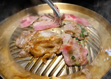 Dilim ızgara domuz Barbekü demir tava ile sebze ve çorba su kapalı düşük aydınlatma ile.