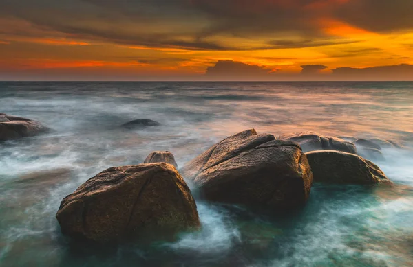 Skała i gładka fala morska w czasie zachodu słońca. — Zdjęcie stockowe