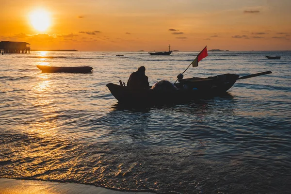 Деревянная рыбацкая лодка, плывущая по морю с закатом . — стоковое фото