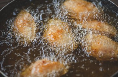 Kızarmış tuzlu tavuk kanadı, demir tavada pişirme yağı ve kapalı alanda hafif ışıklandırma..