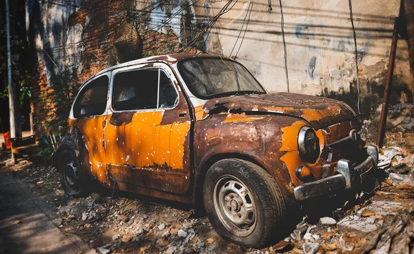 Old and rusty damaged car at the waste with outdoor sun lighting.