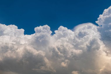 Mavi gökyüzünde ağır bulutlar ve güneş ışığı.