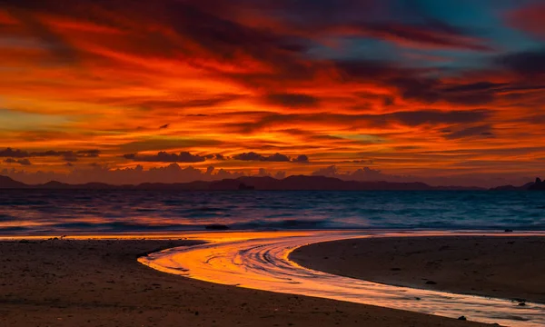 海のビーチや水路で日没の照明で赤い暗い暖かい曇りの空 — ストック写真