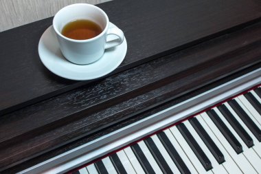 beyaz bir daire ve bir fincan çay piyano açıldı kas üzerinde.
