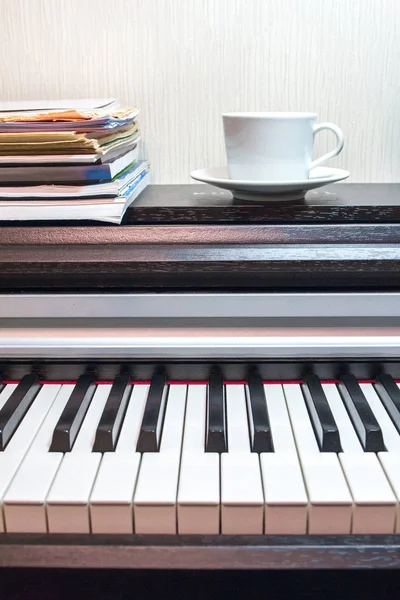 一叠乐谱和一个白色的茶托和一杯茶在勇敢的打开的钢琴上 — 图库照片