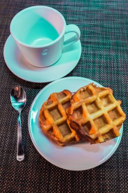 bir tabak, kaşık ve masanın üzerine beyaz bir daire üzerinde yuvarlak Viyana waffle beyaz Kupası.