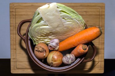 Taze malzemeler tencereye vejetaryen çorba yemek pişirmek için. Lahana, havuç, soğan ve sarımsak pota.