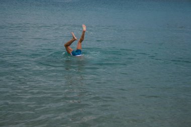 09.20.2008, Hersonissos, Girit, Yunanistan. Genç bir adamın bacakları su üzerinde. Suya dalış bir adam. 