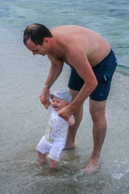 09.25.2008, Hersonissos, Girit, Yunanistan. Yunanistan Seyahat. Genç bir baba ile oğlunun kıyı boyunca yürüme.