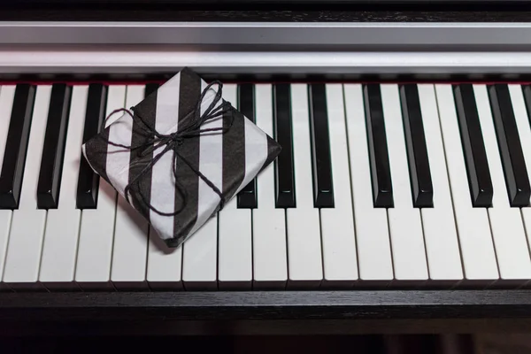 在钢琴键盘上的条纹黑白包装礼品盒 — 图库照片
