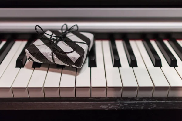 gift box in a striped black and white packaging on the piano keyboard.