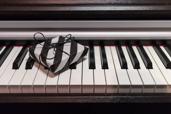 在钢琴键盘上的条纹黑白包装礼品盒 — 图库照片