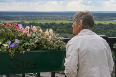 2009.08.29, Vladimir, Rusya Federasyonu. Yaşlı bir kadın çiçek parkta arıyorum. Parkta yürüyüş insanlar. Kadın Bahçe çiçek.