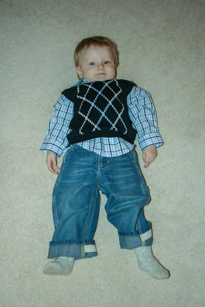 2009 卡鲁加 俄罗斯 有趣的小孩穿着牛仔裤和衬衫躺在地板上 家里的小时装模特儿 — 图库照片